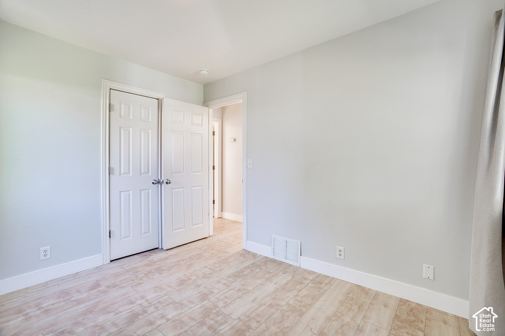 Wood-finish flooring, white trim, light gray walls, and white bi-fold closet doors