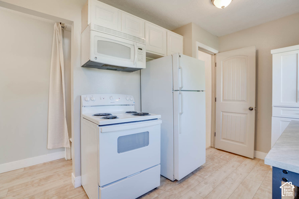 Kitchen featuring white cabinetry, wood-finish flooring, white refrigerator, white range, and a built-in microwave