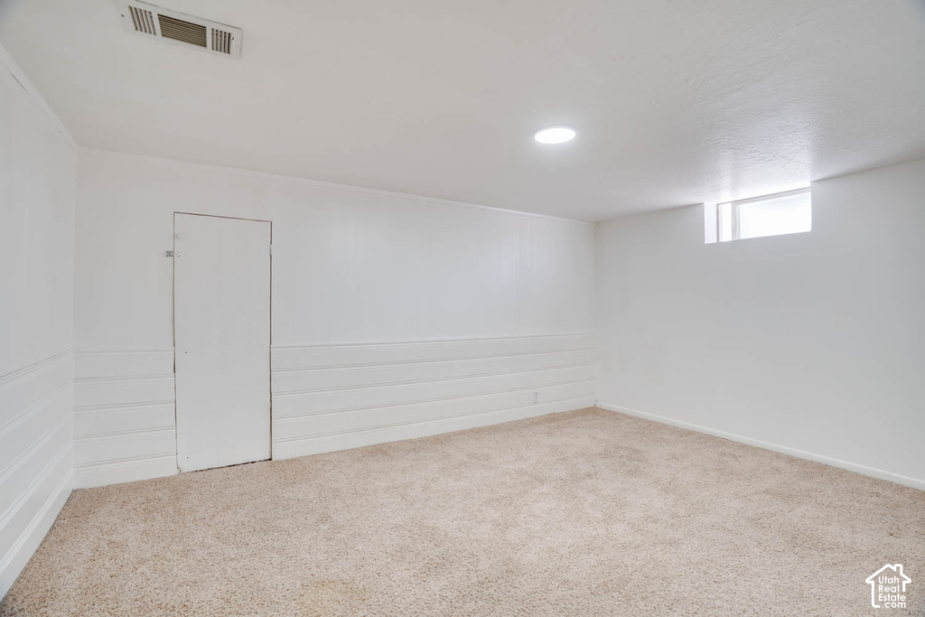 Recessed lighting, light-toned carpeting, white painted walls, and a window providing ambient illumination