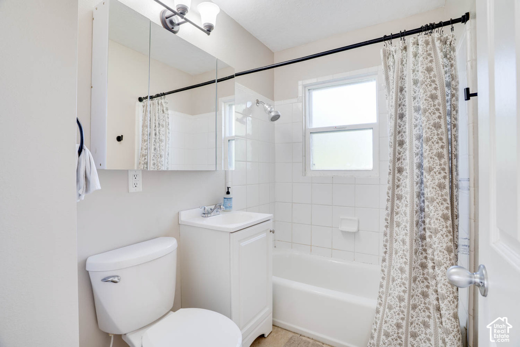White tile shower surround, white bathtub, white vanity with integrated sink, mirrored medicine cabinet, and overhead vanity lighting fixture
