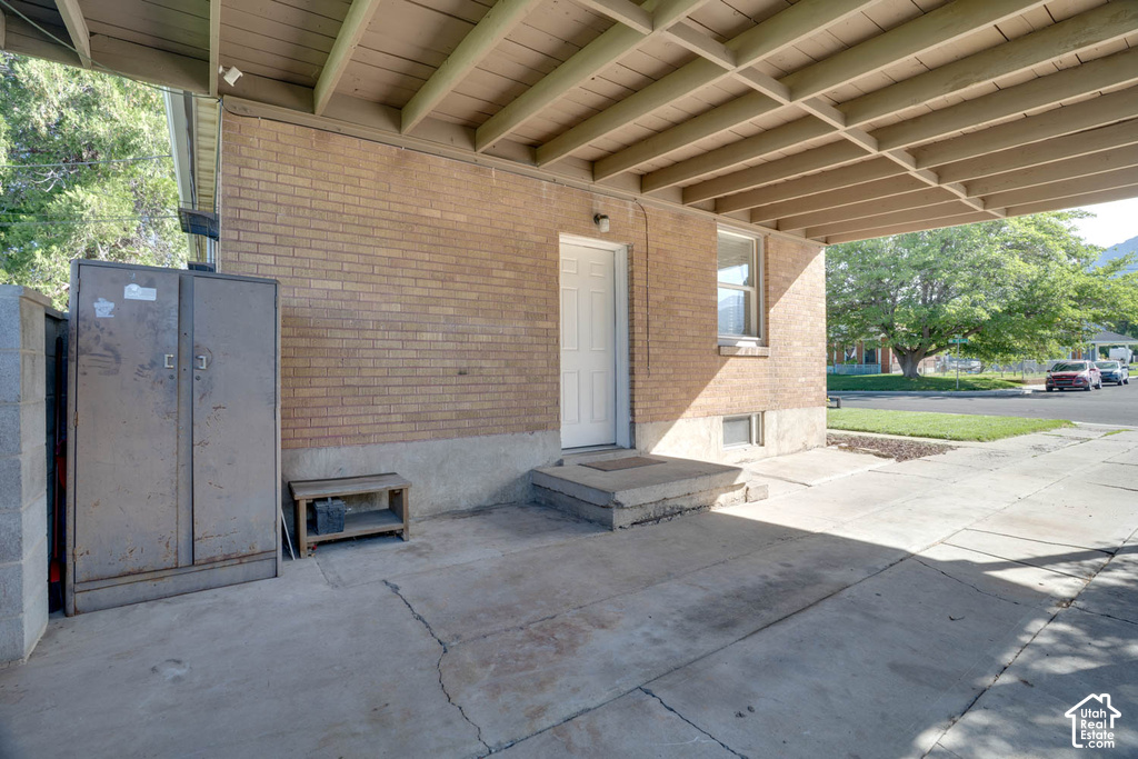 Brick exterior with covered carport, concrete steps, and a white entry door