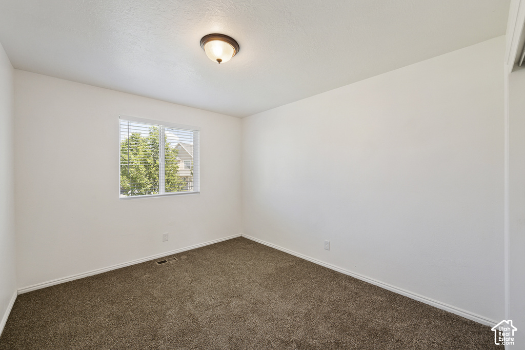 Neutral wall color, brown carpet flooring, flush mount ceiling light fixture, window with blinds