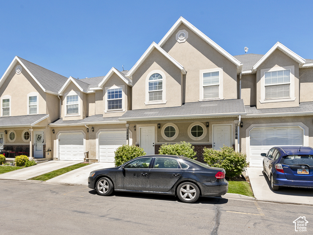 Stucco exterior with gabled roofline, arched and circular windows, attached garages, and concrete driveways