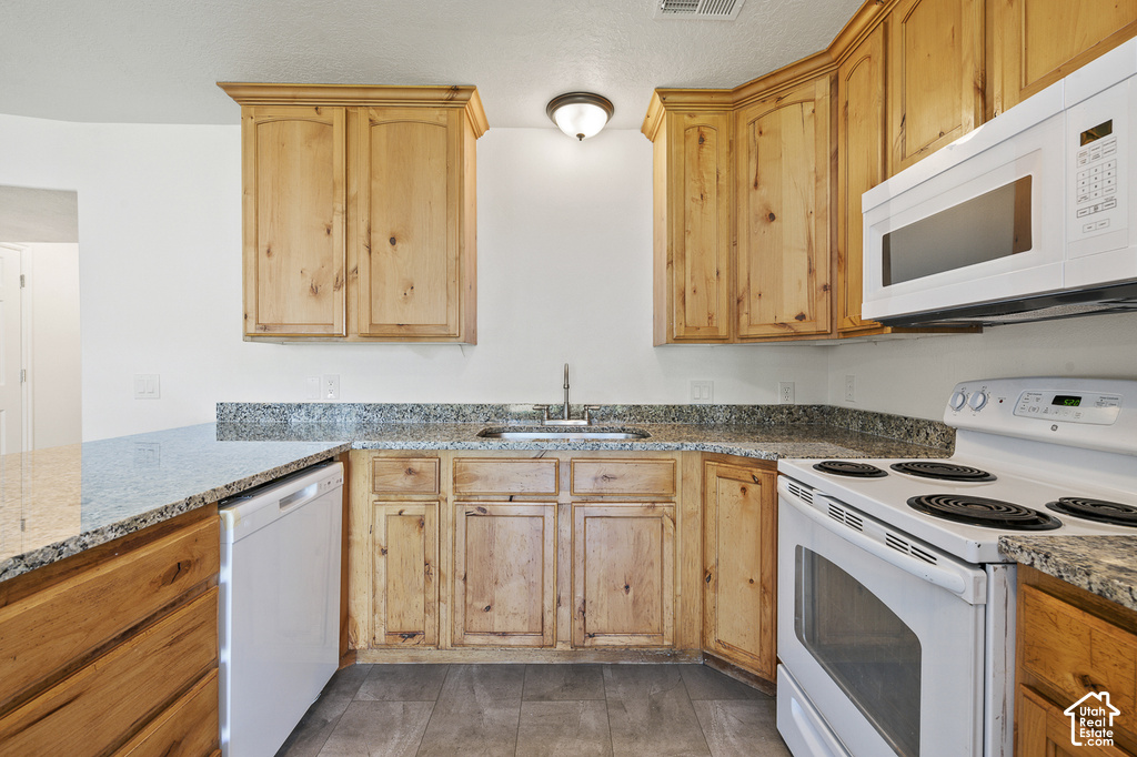 Wood cabinetry, speckled countertops, stainless steel sink, white electric range, and integrated dishwasher