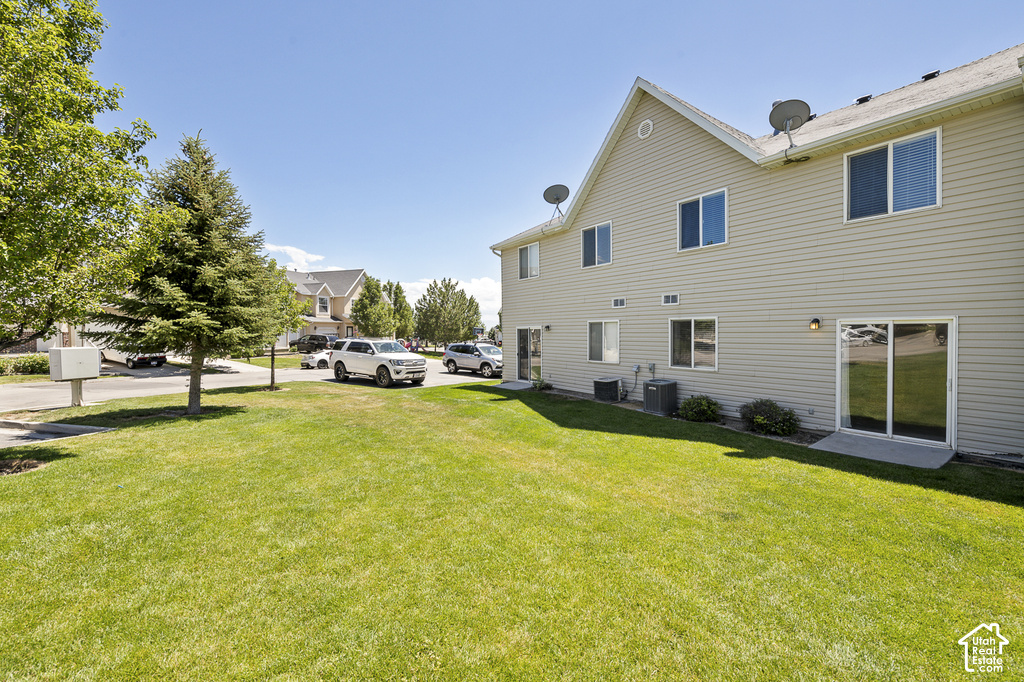 Vinyl siding exterior with multiple windows, two sliding glass doors, and a well-maintained lawn