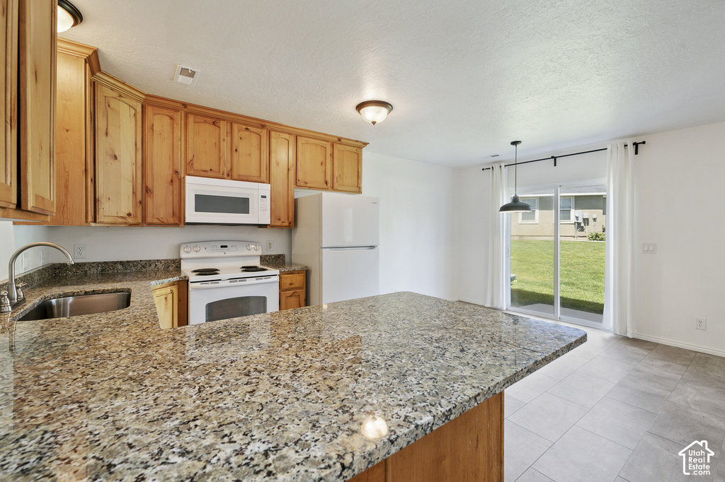 Kitchen featuring wood cabinetry, a stainless steel sink, granite-style countertops, and white appliances