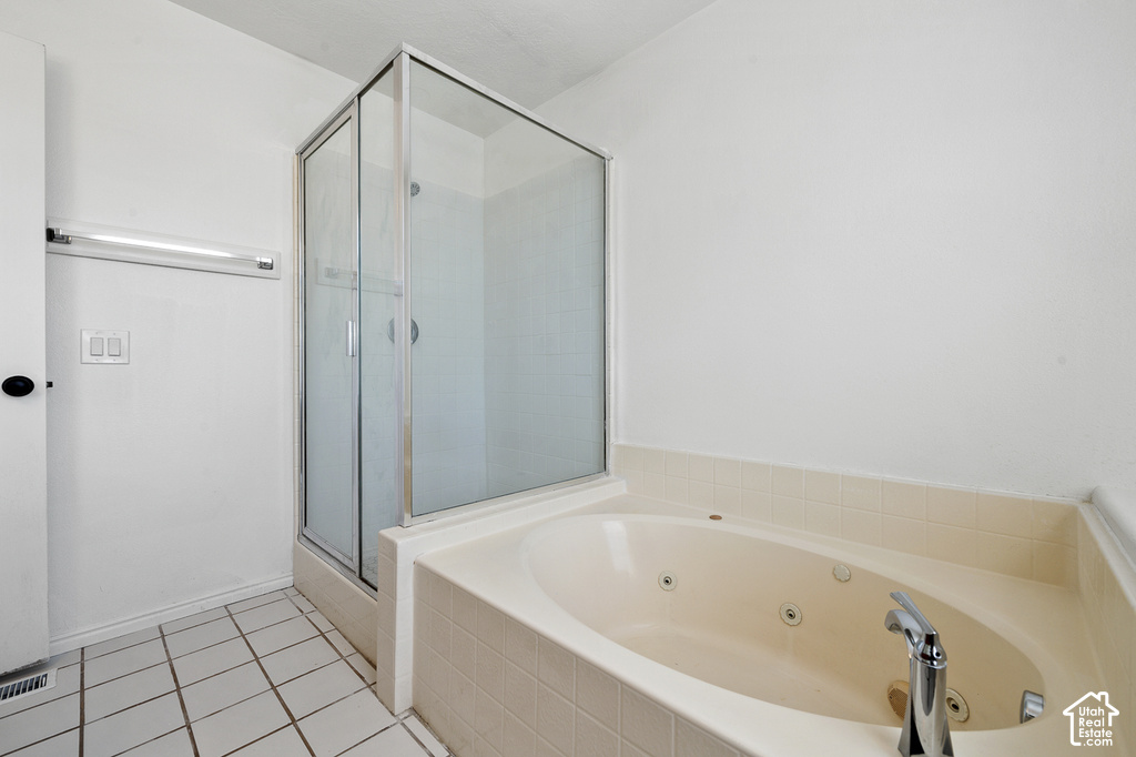 Built-in jetted tub with chrome fixtures, tiled surround, and a glass-enclosed shower