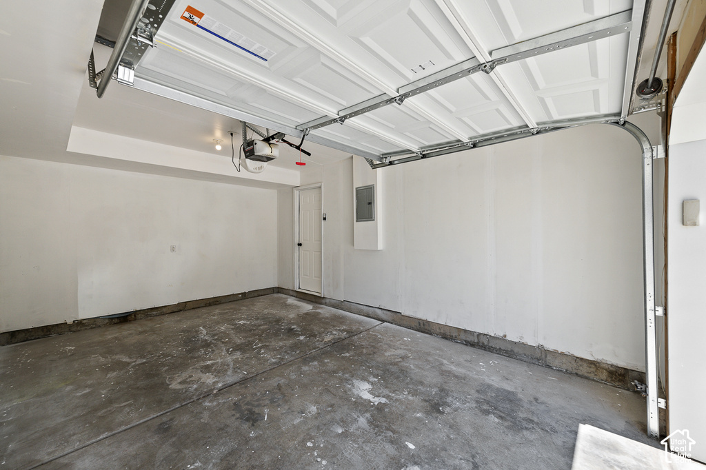 Attached garage featuring concrete flooring, an automatic garage door opener, and a side access door