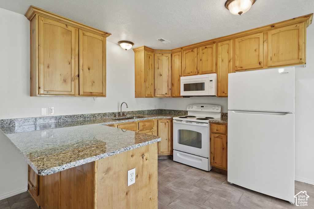 Kitchen featuring wood cabinetry, light-toned countertops, white appliances, and tiled flooring