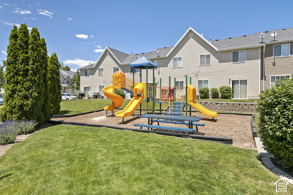 Community recreational area featuring a playground, picnic table, and landscaped green space