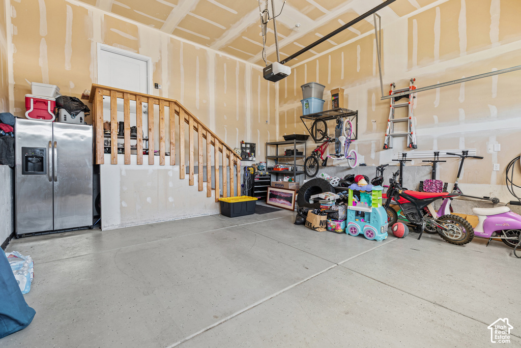 Concrete flooring, natural wood-finish staircase with balusters, overhead garage door track system, overhead garage door opener