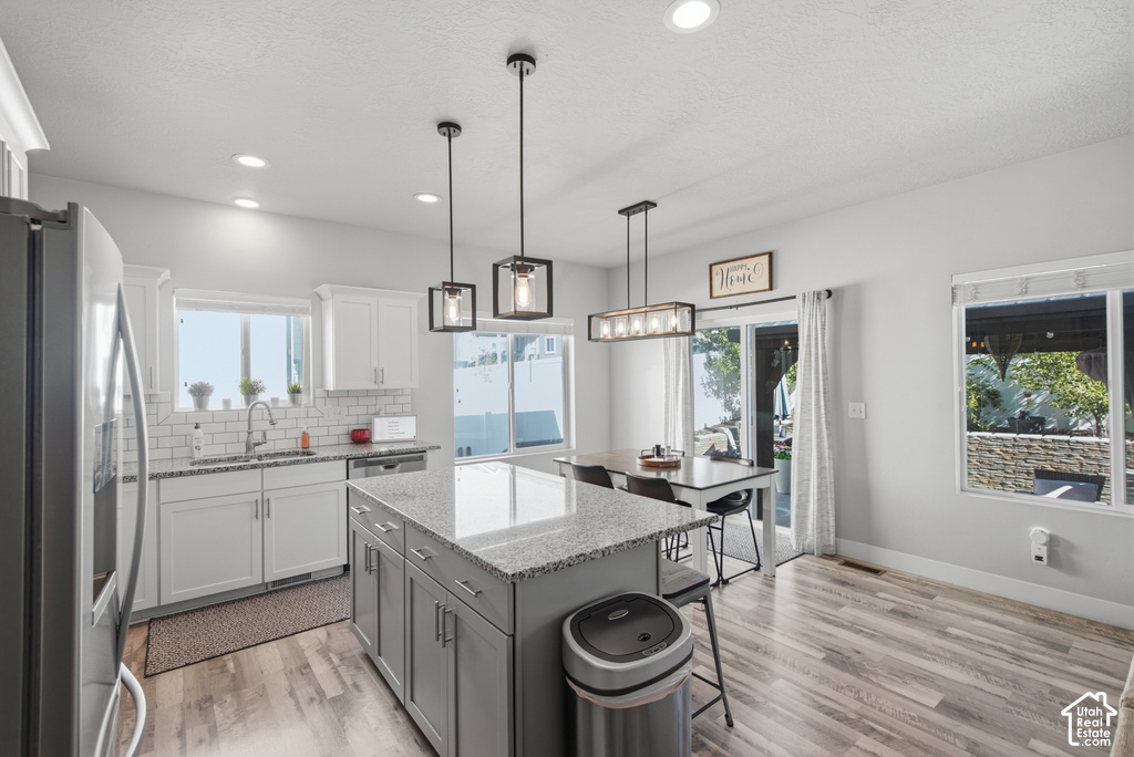 Kitchen featuring a central island with a granite countertop, wood-finish flooring, white cabinetry, recessed lighting, and a subway tile backsplash