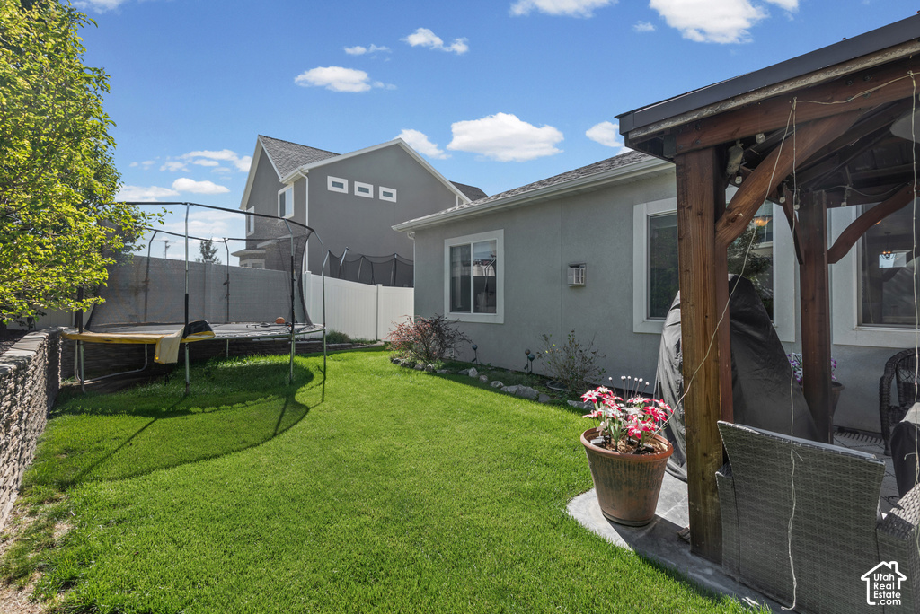 Expansive green lawn, stucco exterior, white window trim, and a covered patio area with exposed wood beams