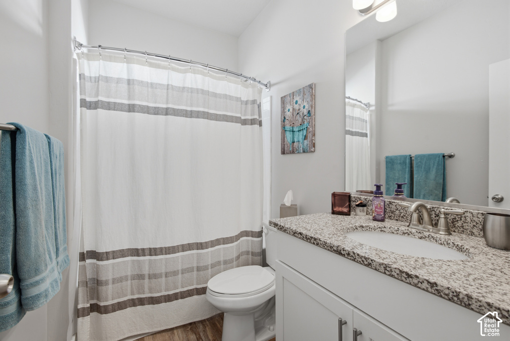 Bathroom featuring a single vanity with a speckled countertop, undermount sink, and brushed nickel faucet