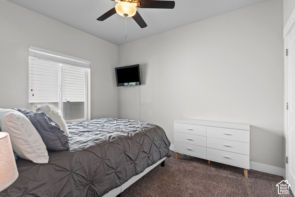 Carpeted room featuring a ceiling fan with integrated lighting, a window with horizontal blinds, and a built-in wall-mounted television bracket