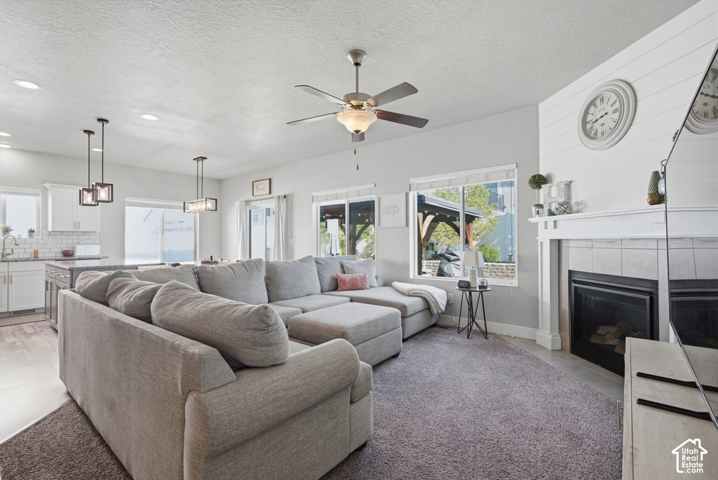 Living area featuring a fireplace with a mantel, shiplap accent wall, and a ceiling fan
