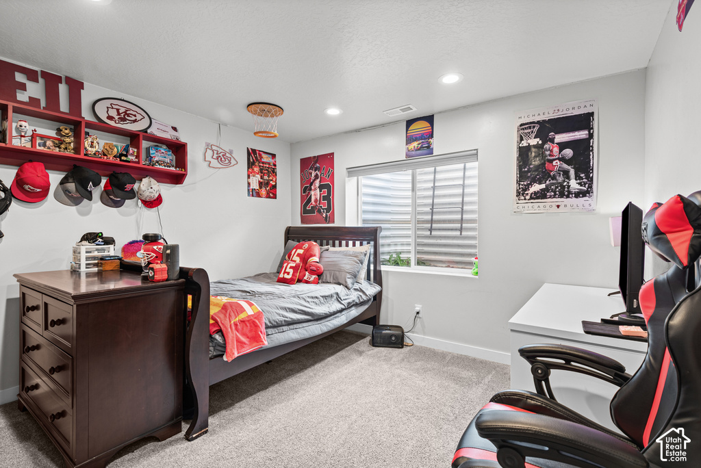 Recessed lighting illuminates neutral-toned walls and plush carpeting, complemented by a window with horizontal blinds
