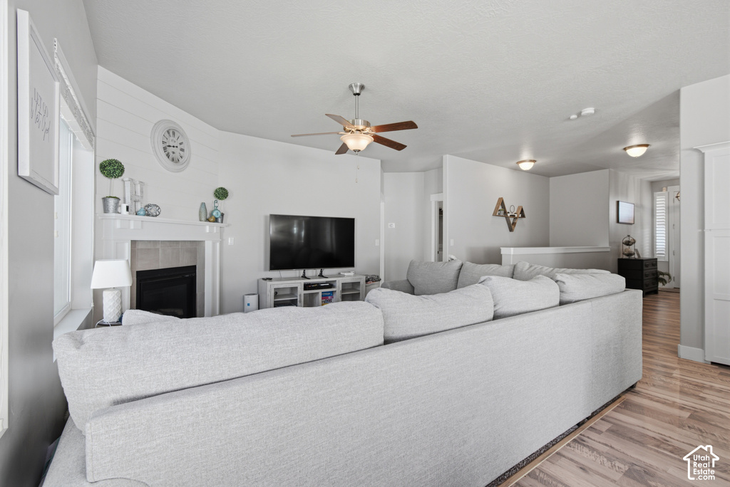 Living area featuring a fireplace, wood-finish flooring, a ceiling fan, and recessed lighting