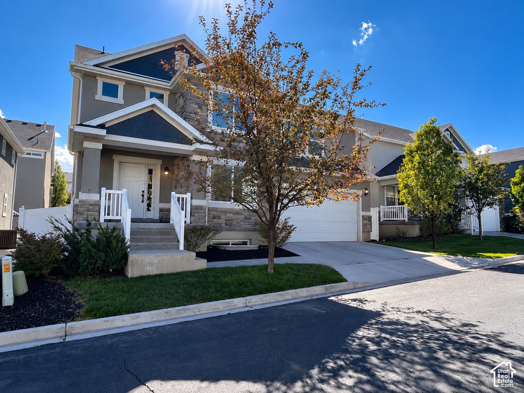 Multi-level residence featuring a stone and stucco exterior, prominent two-car garage, and a covered front porch with white railings