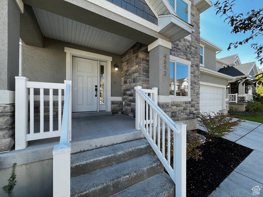 Multi-level facade featuring stone and stucco accents, a covered entry, and white exterior railings