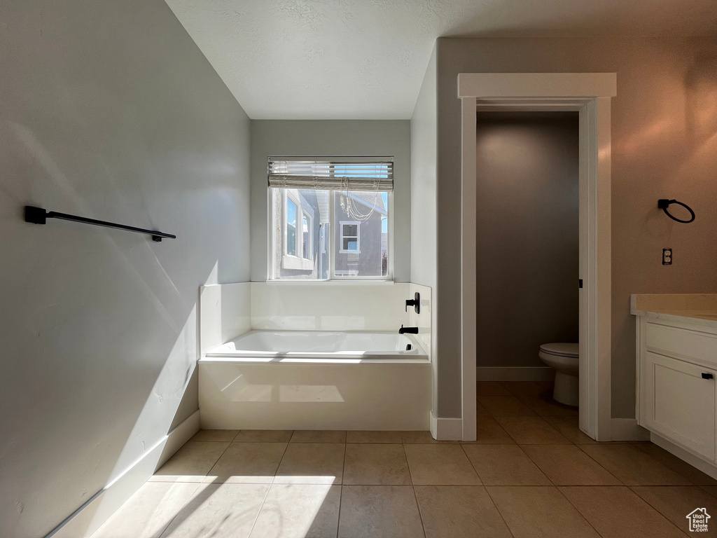 Integrated soaking tub with black fixtures, tile flooring, and a window with blinds