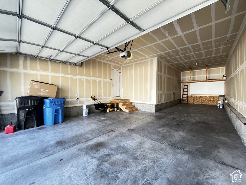Two-car garage with concrete flooring, automatic garage door, and recessed lighting