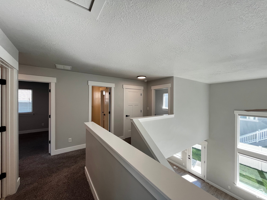 Upper-level landing with carpeted flooring, white trim, and multiple doorways
