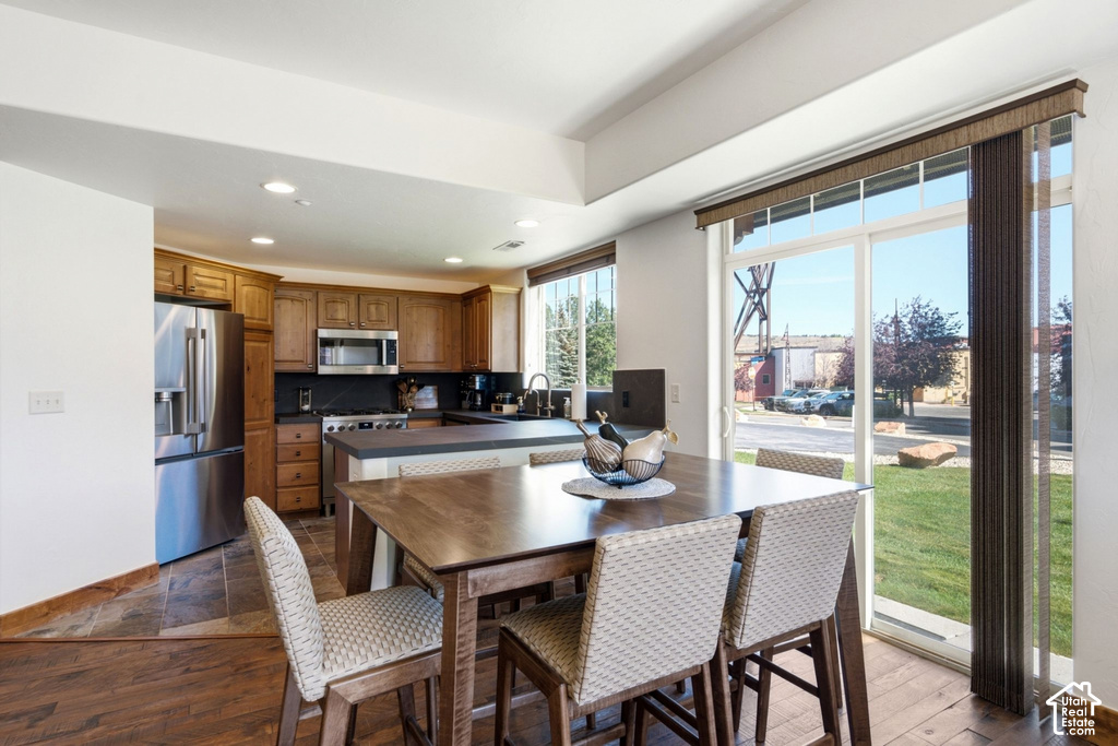 Recessed lighting, wood-finish flooring, stainless steel appliances, sliding glass door, and a kitchen island with seating