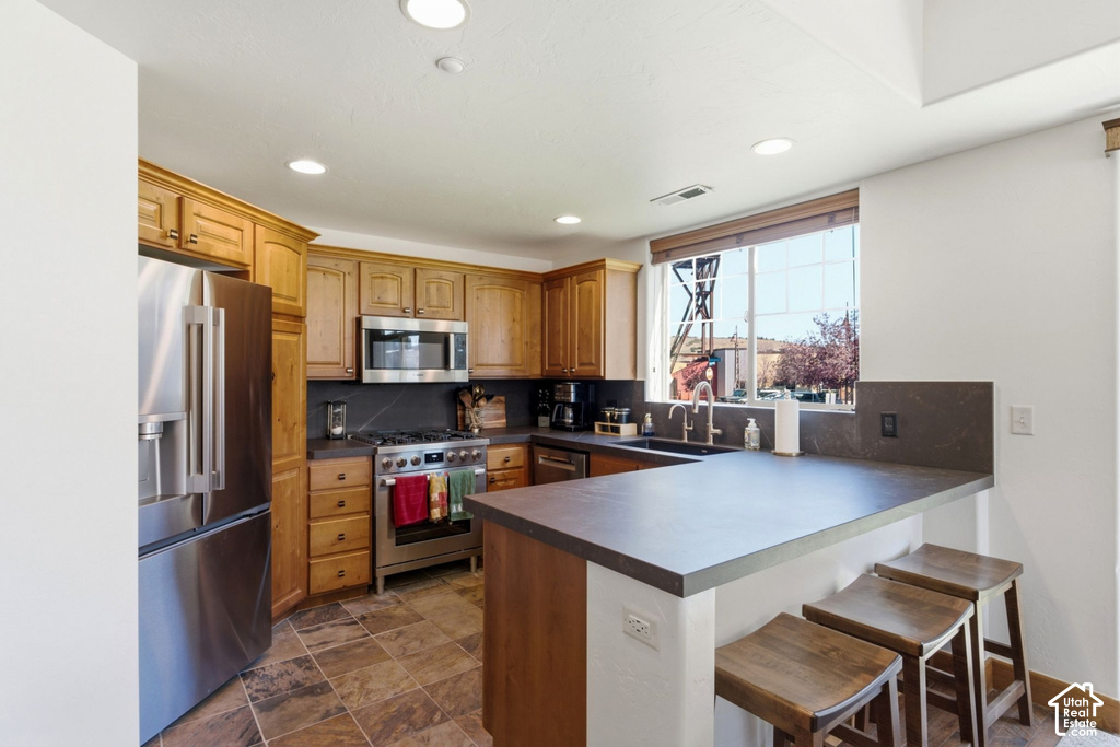 Kitchen featuring wood cabinetry, stainless steel appliances, stone-finish countertops, tile flooring, and recessed lighting