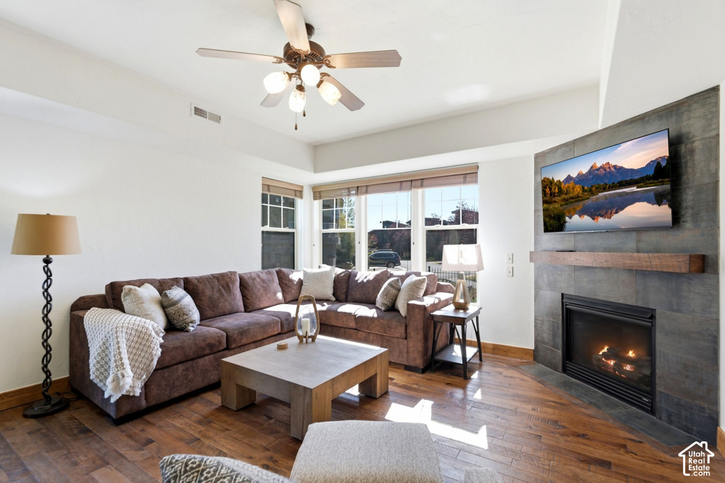 Spacious living area featuring wood-finish flooring, a ceiling fan with integrated lighting, and multiple windows