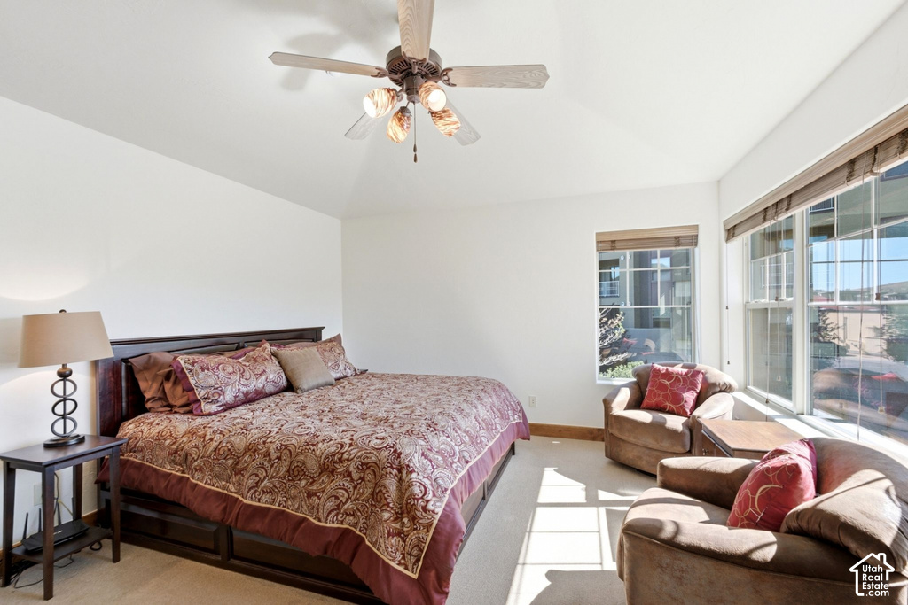 Vaulted ceiling with a ceiling fan, multiple windows with blinds, and carpet flooring