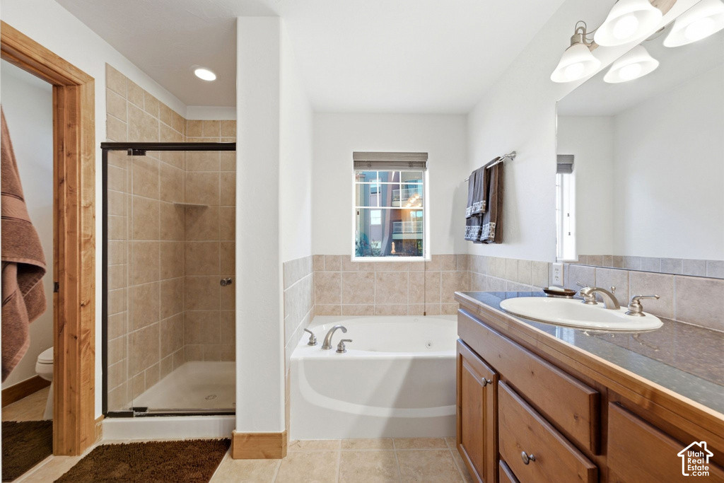 Bathroom featuring a tiled shower enclosure with a glass door, a built-in bathtub, a vanity with a drop-in sink, and a framed mirror