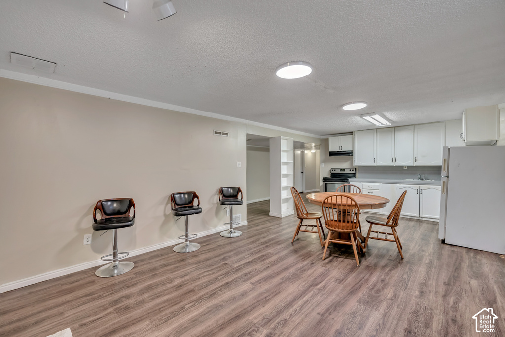 Open-concept living space with wood-finish flooring, recessed lighting, and a full kitchen featuring white cabinetry and appliances