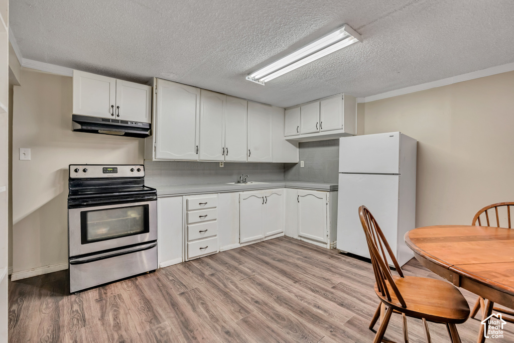 Kitchen featuring white cabinetry, wood-finish flooring, stainless steel range, and a white refrigerator