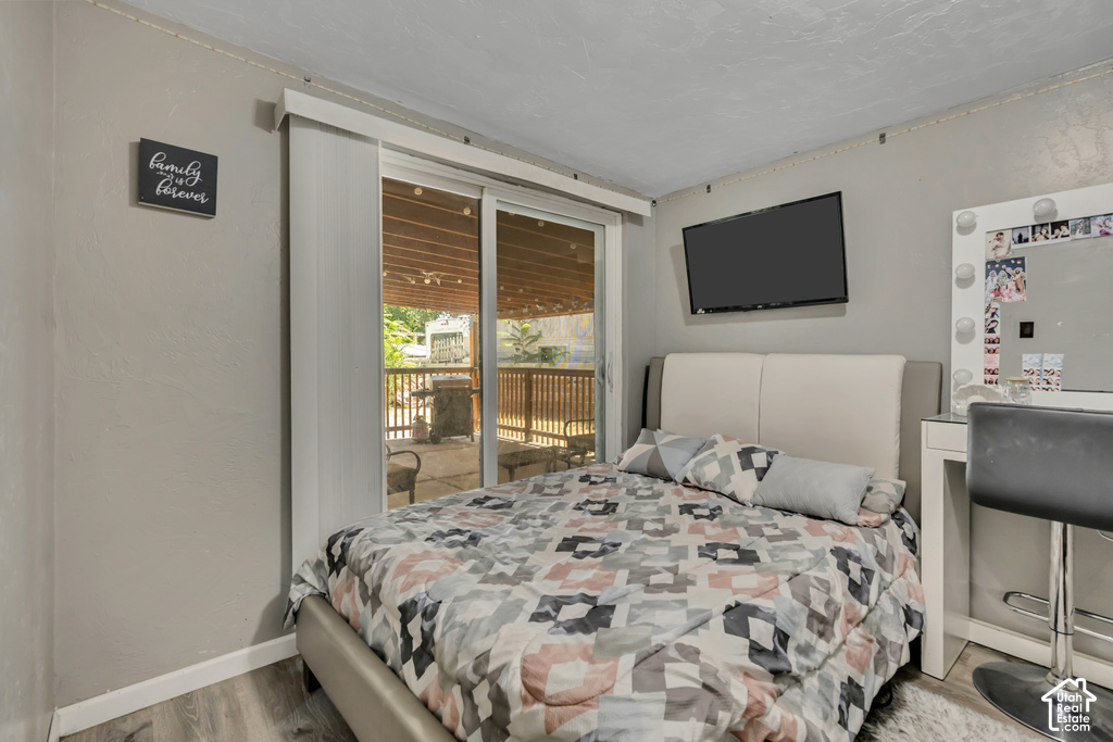 Sliding glass door access to an exterior deck, wall-mounted television, and wood-finish flooring