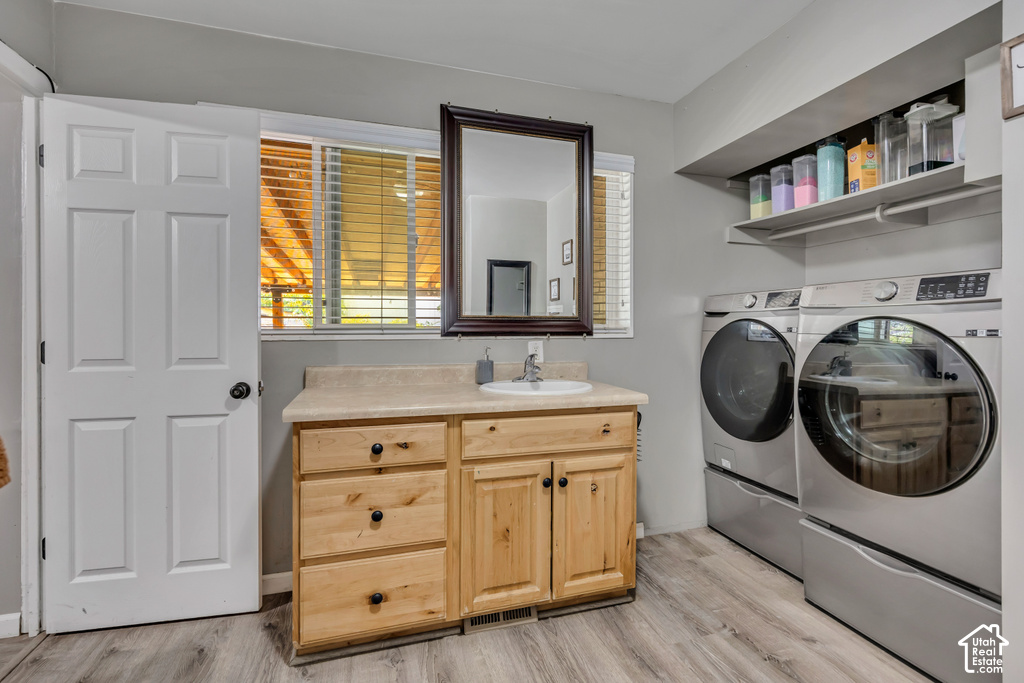 Wood-finish flooring, light wood vanity with an integrated sink, framed mirror, and upper shelving