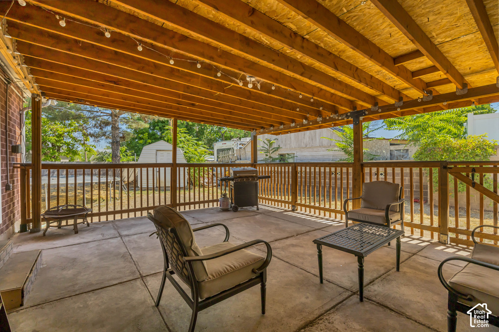Covered patio with a concrete slab, wood-beamed ceiling, and wood railing