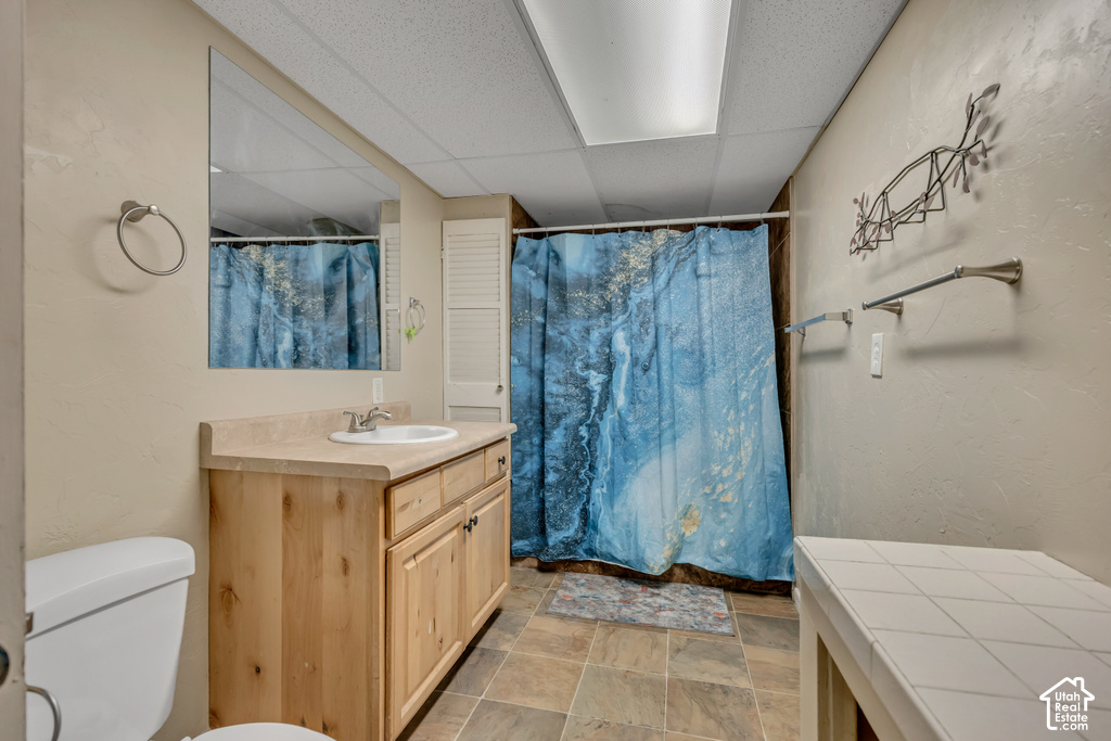 Bathroom with wood-finish vanity, integrated sink, and square tile flooring