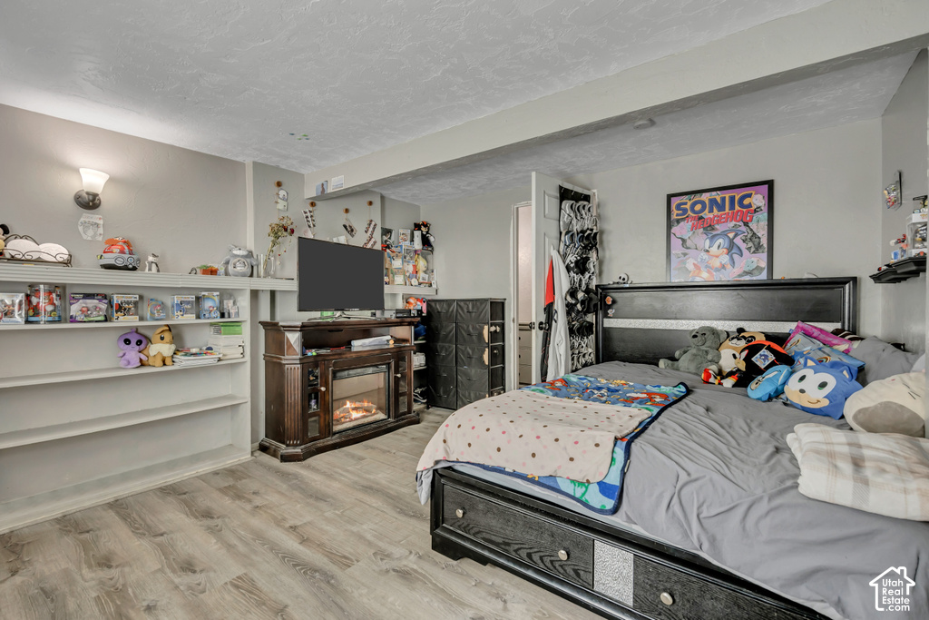 Wood-finish flooring with built-in shelving, a wall sconce, and an entertainment console featuring an electric fireplace