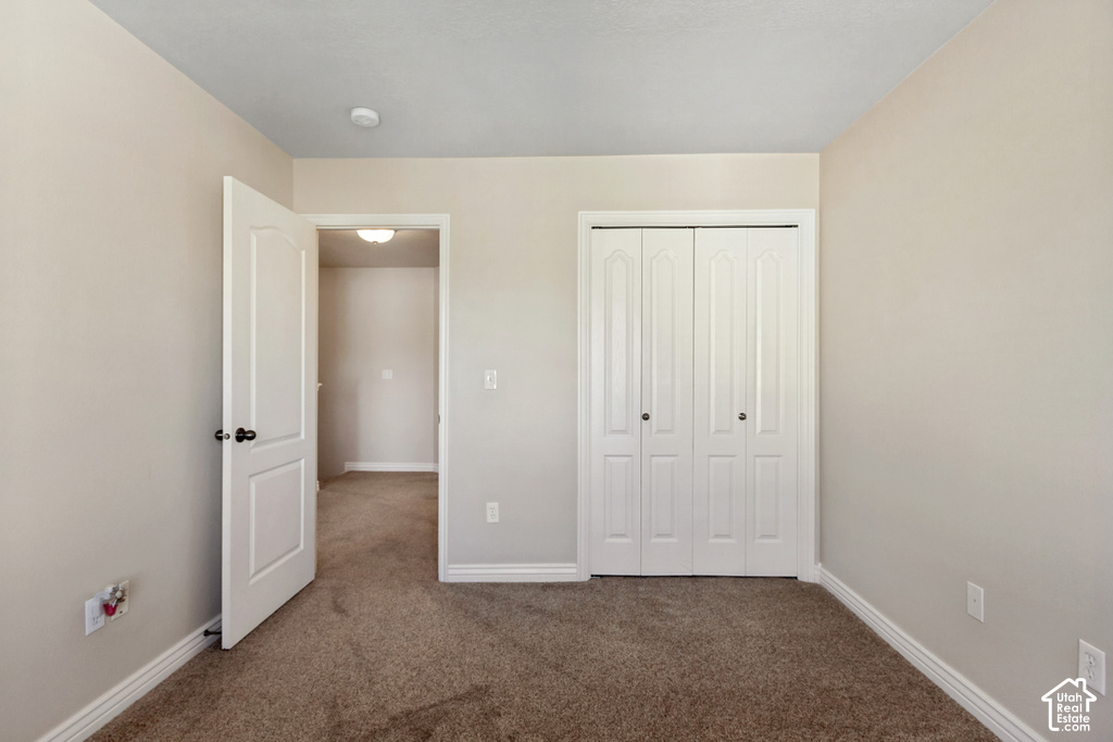 Carpeted flooring, bi-fold closet doors, white interior door, light neutral wall paint, and white trim