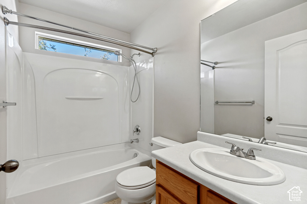 White fiberglass tub and shower combination with chrome fixtures, a transom window, and a wood-finish vanity with an integrated sink