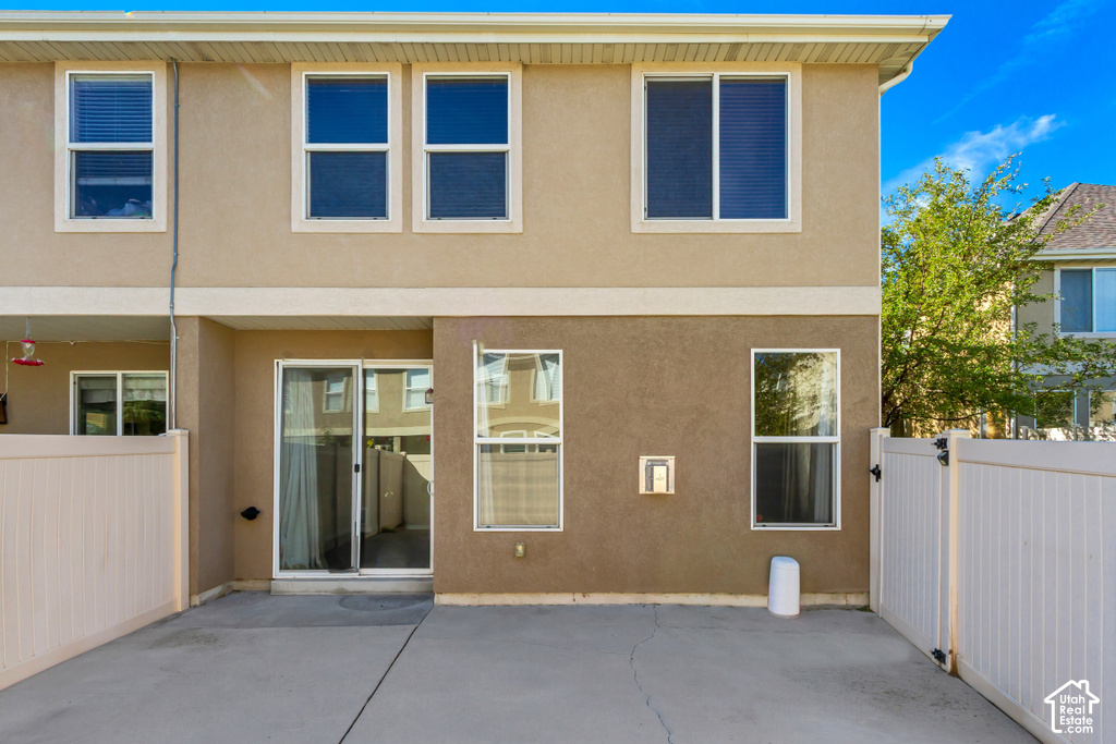 Concrete patio with white privacy fencing, ground-level sliding glass door, and upper-level windows