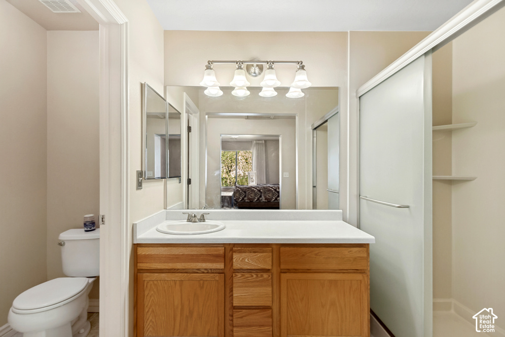 Vanity with wood-finish cabinetry and white countertop, undermount sink with chrome faucet, large mirror, and four-light vanity fixture