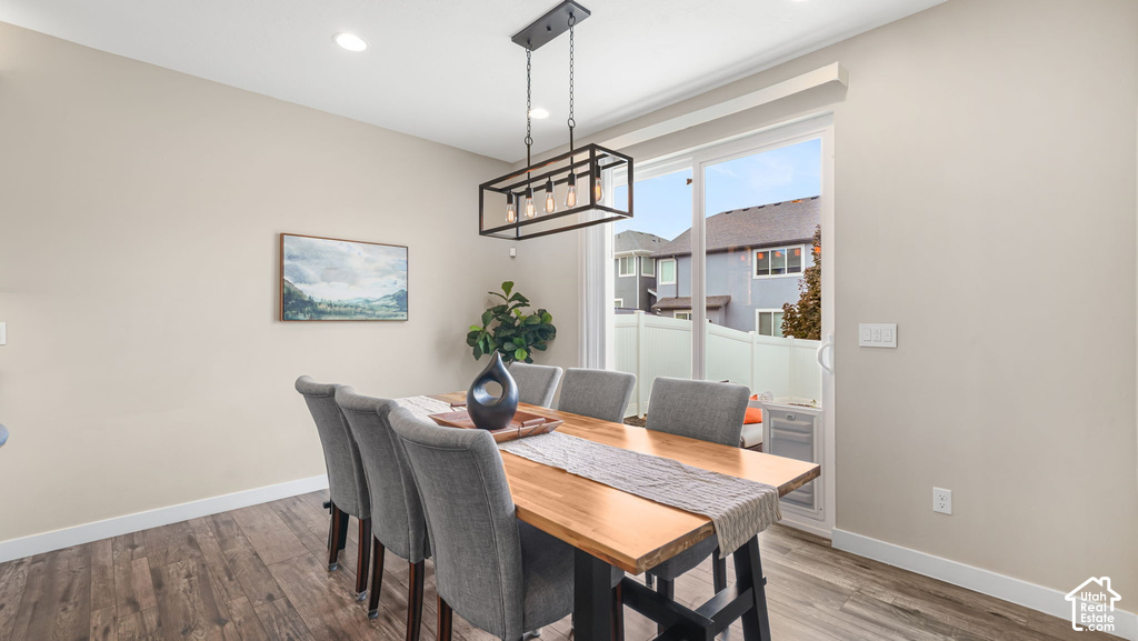Dining area featuring wood-finish flooring, recessed lighting, and a linear chandelier