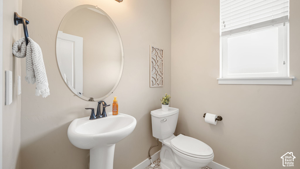 Pedestal sink with dark bronze fixtures, oval vanity mirror, and window with blinds