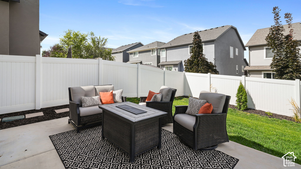 Concrete patio with a white privacy fence, manicured lawn, and landscaped garden beds