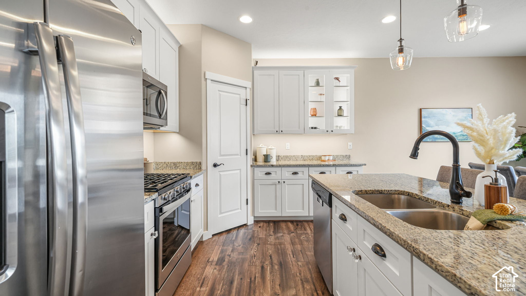Kitchen featuring stainless steel appliances, granite countertops, wood-finish flooring, white cabinetry, and a double basin sink