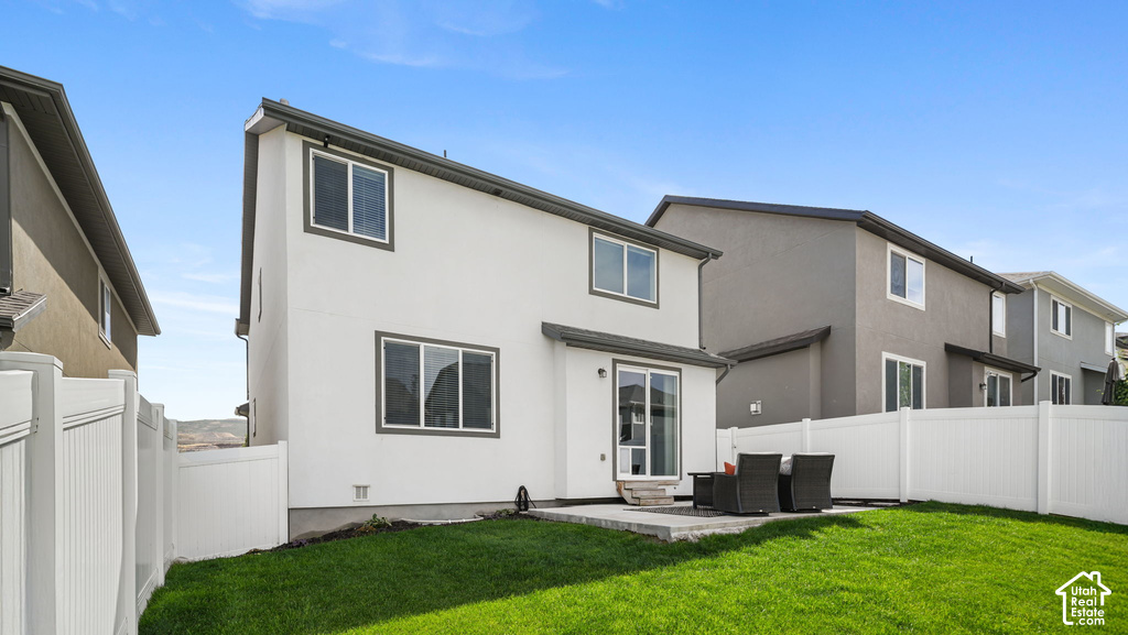 Expansive lawn with a white privacy fence, concrete patio, and stucco exterior