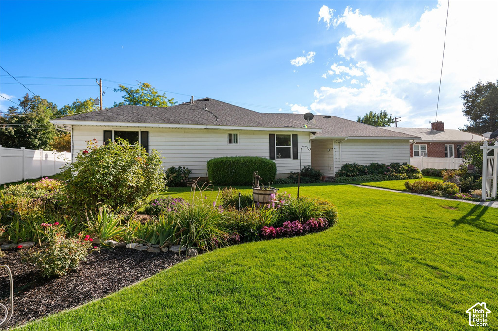 Expansive front yard featuring a manicured lawn, established landscaping, white vinyl fencing, and a well-maintained exterior