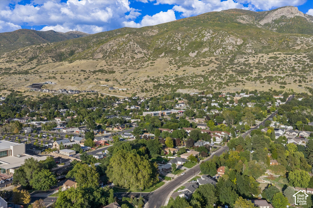 Residential area with varied architectural styles, mature trees, and mountainous terrain